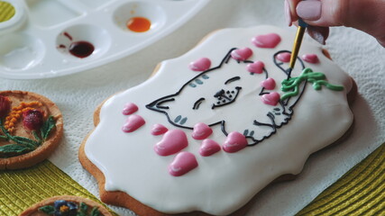 Cookie decorating masterclass with royal icing. Bakery worker decorating gingerbread cookies.