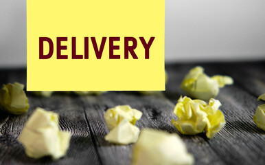 Delivery - text on yellow note sheets on a dark wooden background with crumpled sheets