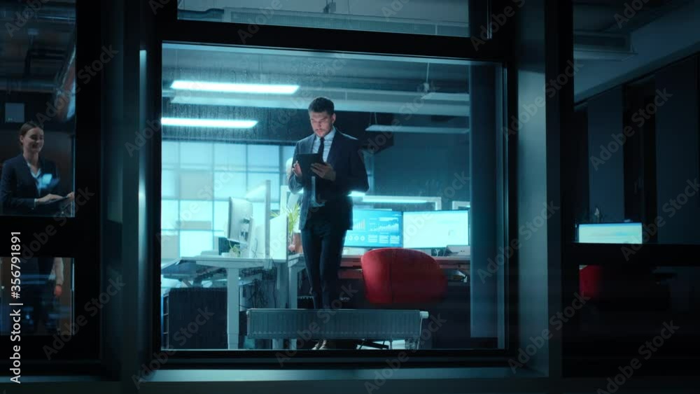 Poster Footage from Outside: Businessman Working on a Digital Tablet Computer in the Office. Manager Checking Emails while Standing by the Window. Employee Planning Financial Tasks and Business Development.