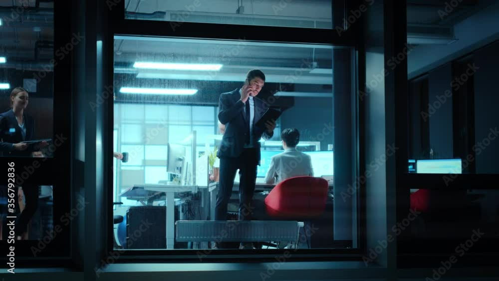 Poster Footage from Outside: Businessman Working on a Tablet Computer in the Office. Manager Talks on the Mobile while Standing by the Window. Employee Planning Financial Tasks and Business Development.
