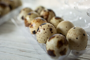 A closeup view of several quail eggs in a plastic carton.