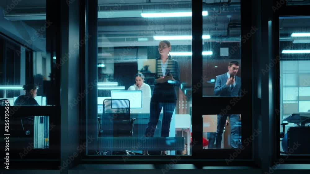 Aufkleber Footage from Outside: Businesswoman Working on a Tablet Computer in the Office. Manager Checking Emails while Standing by the Window. Employee Planning Financial Tasks and Business Development.