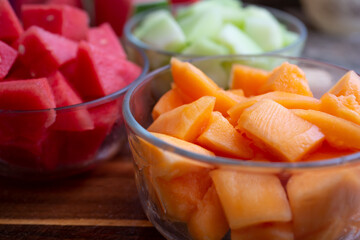 A view of several glass bowls of chopped melon, featuring cantaloupe.