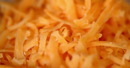 Small pieces grated cheddar cheese fall in a heap. - Powered by Adobe