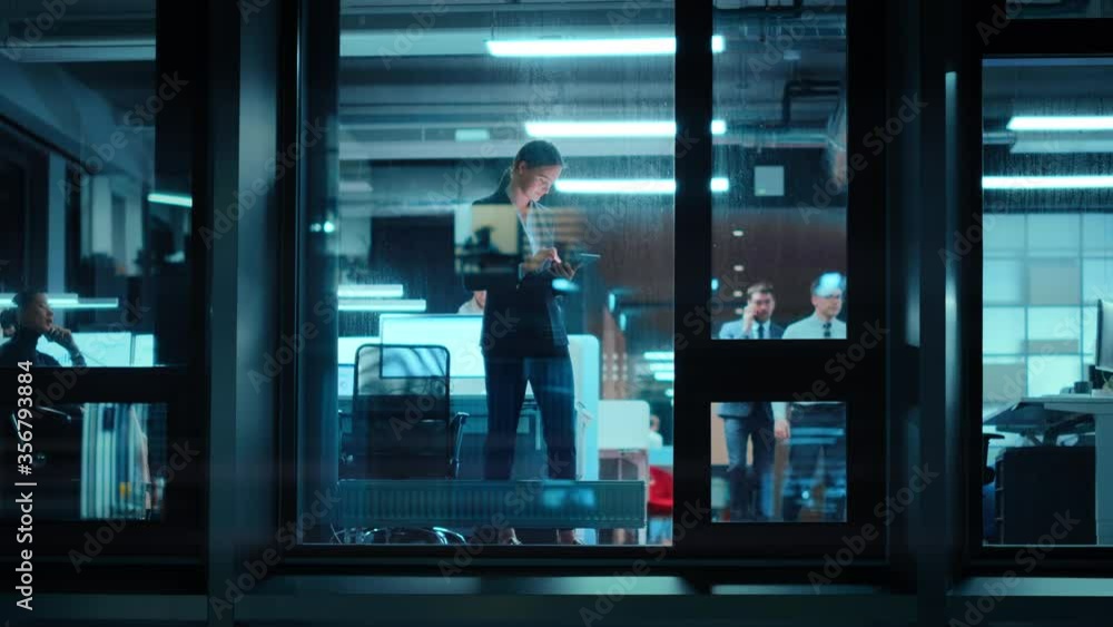 Poster Footage from Outside: Businesswoman Working on a Tablet Computer in the Office. Manager Checking Emails while Standing by the Window. Employee Planning Financial Tasks and Business Development.
