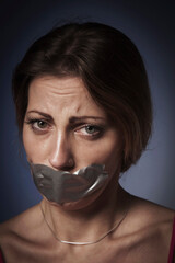 lack of freedom and independence concept. Psychological portrait of scared woman with  mouth covered with a plaster.