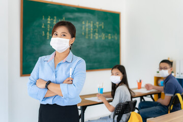 Asian woman teacher wearing masks to prevent the outbreak of Covid 19 in classroom with student while back to school reopen their school, New normal for education concept..