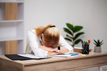 Tired young businesswoman exhausted at workplace in her office