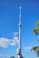 Obraz premium A mast with telecommunication equipment on a background of blue summer sky.