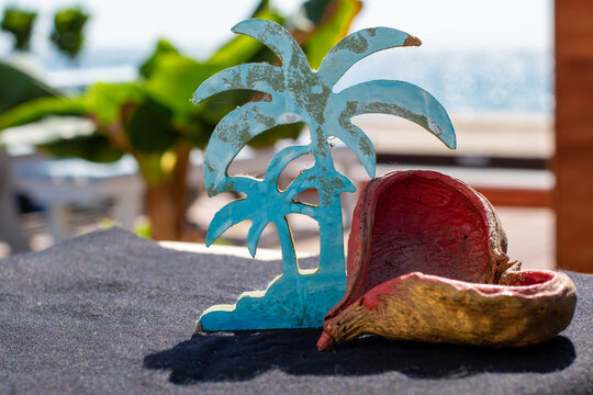 Painted Carved palm tree with heart nut shell and ocean background on a black base.