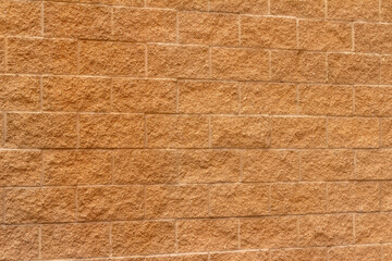 Modern stone block wall wall background with a golden brown color and textured surface