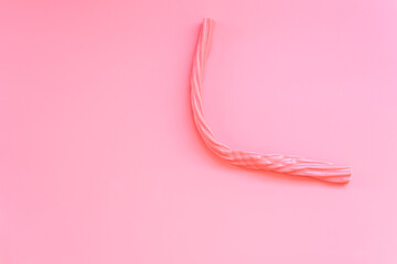Elongated pink candy isolated on a flat colored background.