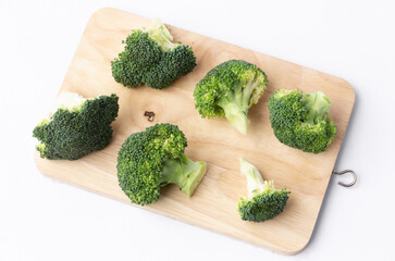 fresh broccoli on wooden cutting board on white background.