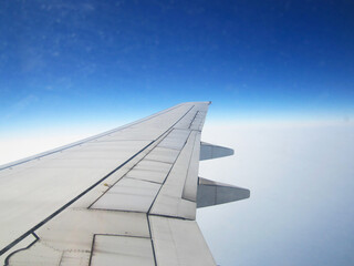 Fototapeta premium Window View of Airplane Wing in Flight with Blue and White Horizon