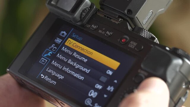 Closeup of a photographer using his professional photography camera device to scroll through settings menu .