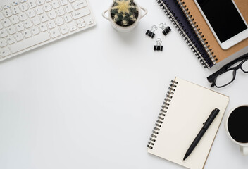 Top view above of White office desk table with keyboard, notebook and coffee cup with equipment other office supplies. Business and finance concept. Flat lay with blank copy space.