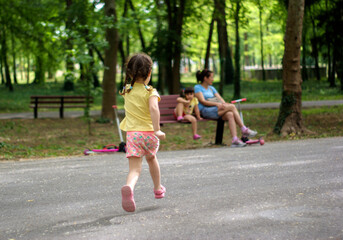 Fototapeta premium A little girl runs down an alley in the park