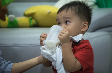 portrait of baby boy holding plastic cup drinking milk 