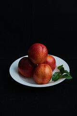 Fototapeta na wymiar Red peaches on white dinner plate. Red nectarine on white dinner plate.