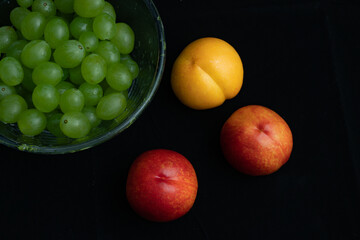 Various fresh fruits on black background.Red nectarine in white dish and yellow peach on black background