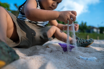 cute young little kid playing sand in the park alone