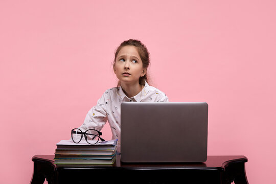 Schoolgirl Sitting Near A Laptop Looking Sideways With Tired Eyes.