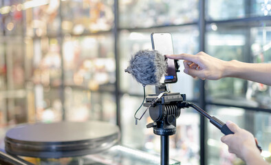 Male hand is shooting a video using gimbal and smart phone on tripod for live about the product for...