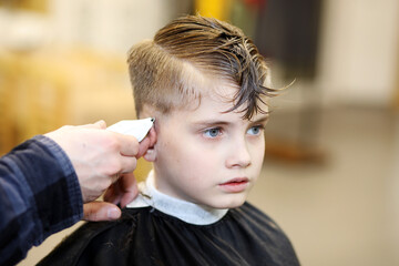Professional hairdresser cutting childs hair in beauty saloon