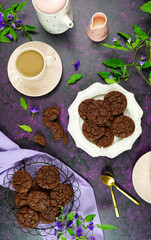 Serving freshly baked double chocolate chip homemade cookies on pink tray with tea and coffee, creative concept flat lay. Top view overhead vertical orientation.