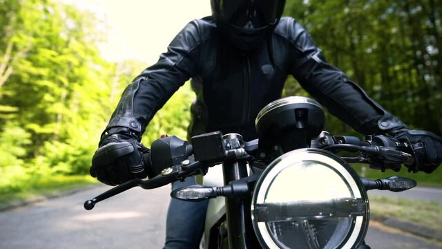 All-black motorcycle rider let the engine roar - reven - playing on the throttle and set off in a forest - Hero tracking shot