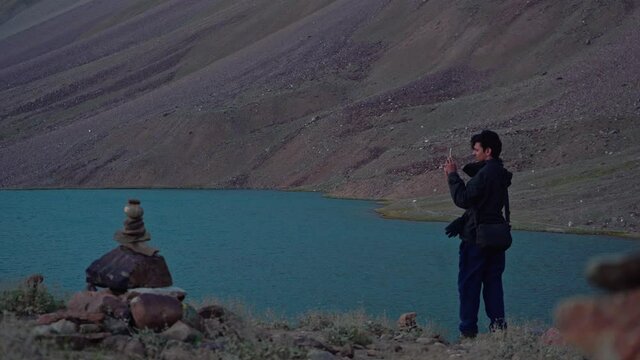Beautiful frame of a man sitting and clicking pictures at a beautiful himalayan lake , spiti valley
