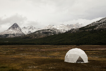 Campsite. Camping dome in the meadow at the foot of the Andes mountains with snowy peaks, in autumn.
