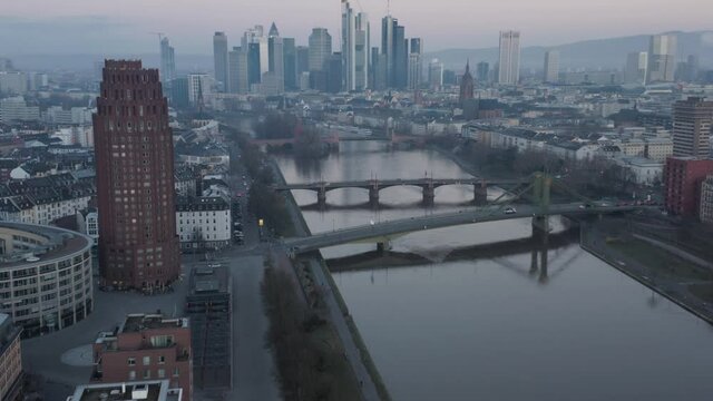 Reveiling the Frankfurt Skyline with Hotel tower and river main in the foreground at dusk on a misty winter morning. Drone Aerial Reveiling Push In