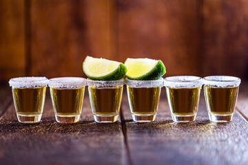 several glasses of tequila lined up, a drink of Mexican culture, made of distilled alcohol, lemon,...