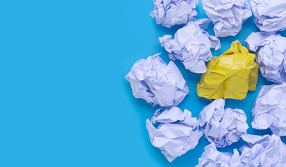 White and yellow crumpled paper balls on a blue background. Top view