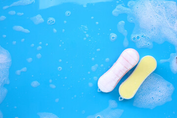 Brush for cleaning clothes with foam of powder detergent water dissolution on blue backgrond.