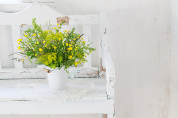 flowers in bucket on old white wooden bench indoor