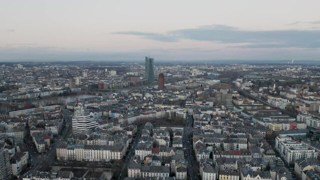 Flying over the Frankfurt am Main District Sachsenhausen towards the EZB european cental bank building skyscraper next to the river main at Sunset in the evening. slow reveiling push in drone aerial