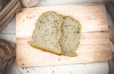Fresh whole wheat bread, cut into pieces, placed on a wooden chopping board and wooden floor table.