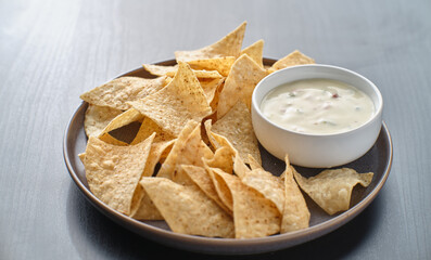mexican hot queso blanco cheese dip with corn tortilla chips on plate
