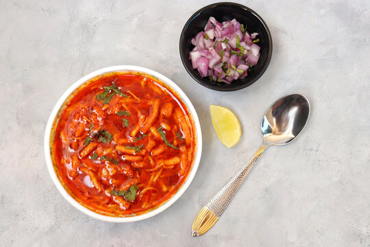 Traditional Sev bhaji or sev tamatar nu Shaak. its a  sweet & spicy tomato curry topped with sev.  Sev is a crisp fried gram flour vermicelli. Served with chopped onion and lemon. with Copy space.