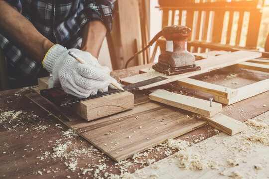 Carpenter working on wood craft at workshop to produce construction material or wooden furniture. The young Asian carpenter use professional tools for crafting. DIY maker and carpentry work concept.