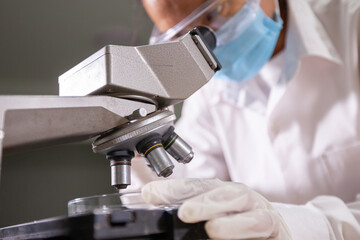 Asian scientist looking through a microscope for research and analysis chemical test in a laboratory