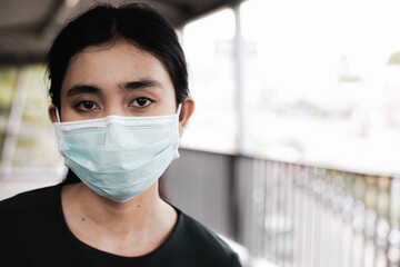 A woman with sad and disappointed eyes at the moment wearing a mask, the doctor stood on the overpass to protect her face during the spread of the Covid-19 virus.