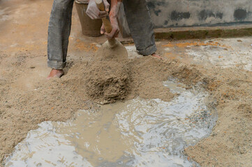 Indian labour mixing cement and water manually on floor using a shovel. Stock image.