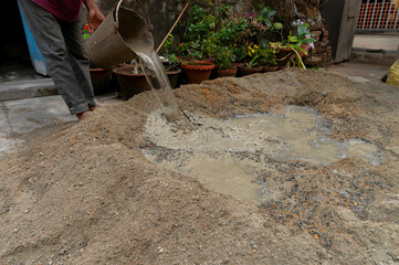Indian labour mixing cement and water manually on floor using a shovel. Stock image.