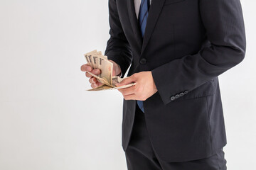 スーツを着た男性が10万円数えている　給付金　援助　コロナ　man money business