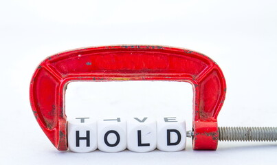 The term hold in black text held in a red metal clamp isolated on a clear background image with...