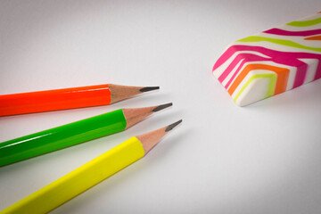 Colorful eraser and simple pencils on a light background. Close up. Selective focus.