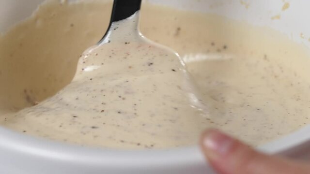 Making gluten free flourless almond chocolate cake, stirring creamy beaten eggs with ground chocolate and almond using spatula